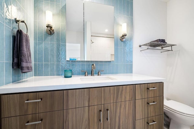 bathroom with toilet, vanity, and tasteful backsplash