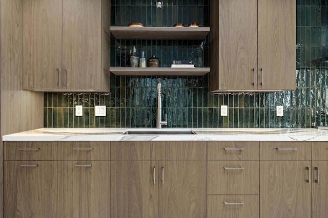 kitchen featuring light stone countertops, sink, and tasteful backsplash