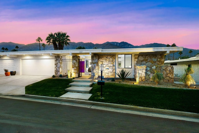 ranch-style house featuring a mountain view, a yard, and a garage