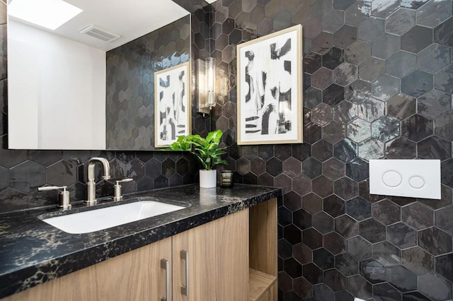 bathroom featuring tile walls, vanity, a skylight, and tasteful backsplash