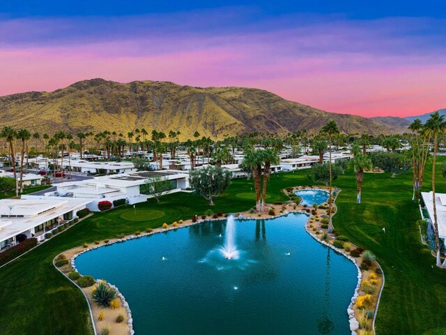 aerial view at dusk featuring a water and mountain view