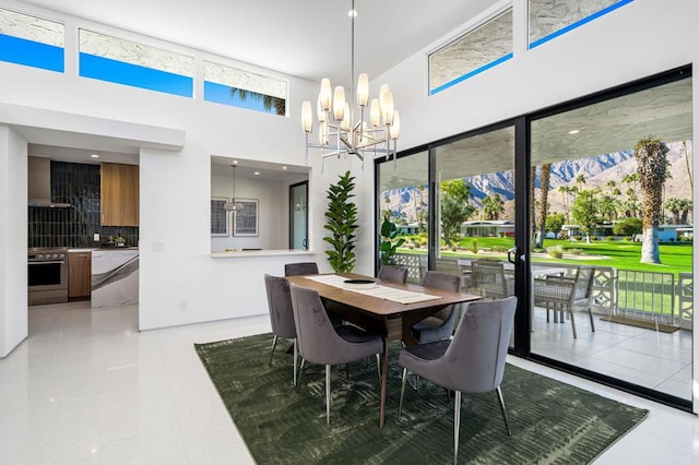 dining area with a mountain view, a notable chandelier, a towering ceiling, and light tile patterned flooring