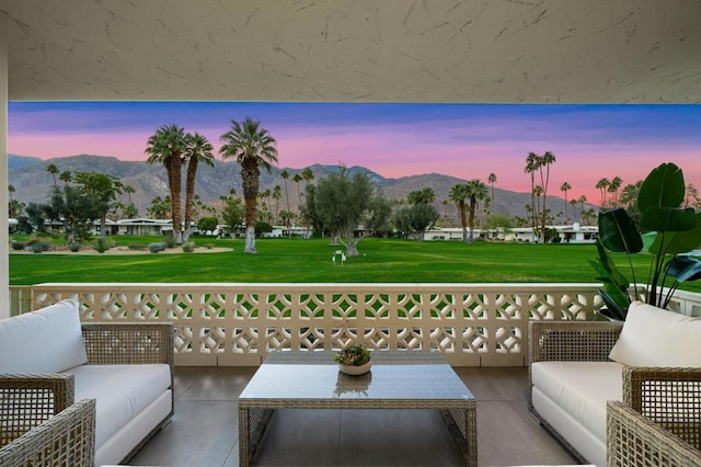 patio terrace at dusk featuring a mountain view, outdoor lounge area, and a yard