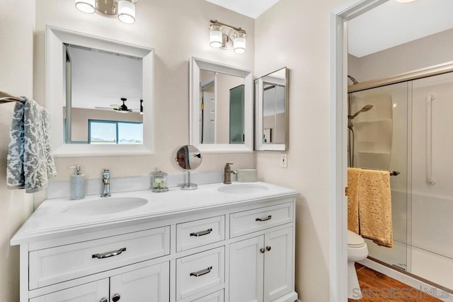 bathroom with toilet, hardwood / wood-style floors, ceiling fan, an enclosed shower, and vanity