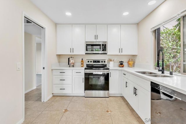 kitchen featuring light tile patterned floors, appliances with stainless steel finishes, sink, and white cabinetry