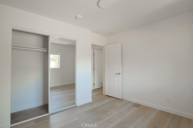 unfurnished bedroom featuring light wood-type flooring and a closet