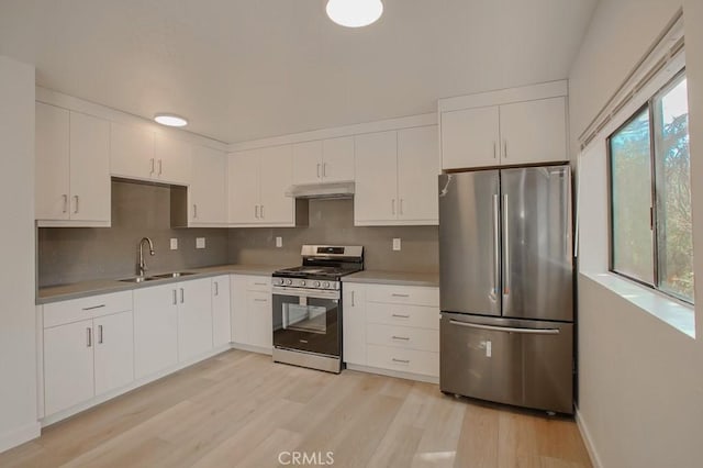 kitchen with backsplash, sink, light hardwood / wood-style flooring, appliances with stainless steel finishes, and white cabinets