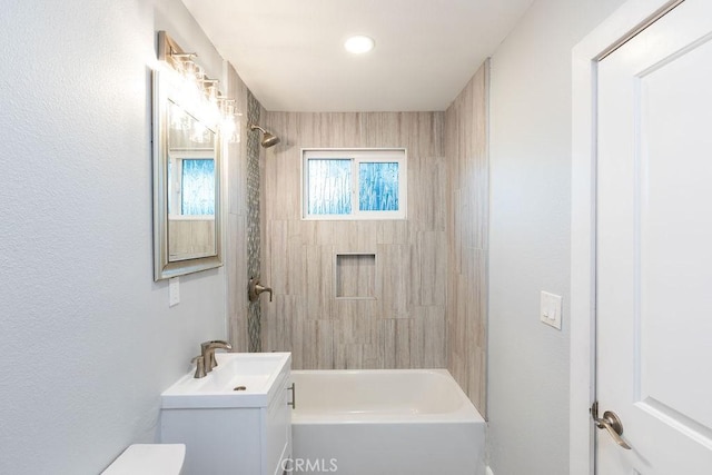 full bathroom featuring toilet, tiled shower / bath, and vanity