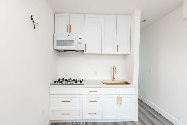 kitchen featuring sink, light hardwood / wood-style floors, white cabinets, and white appliances