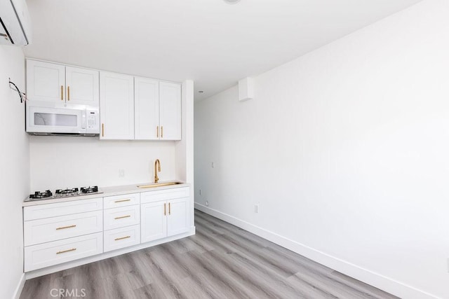 kitchen with light wood-type flooring, sink, white cabinets, and white appliances