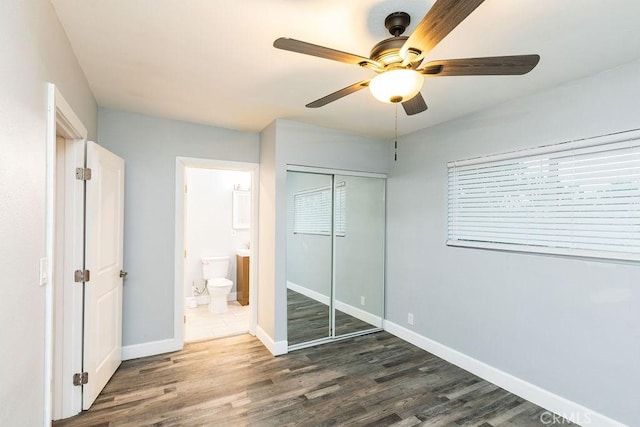 unfurnished bedroom with a closet, ensuite bathroom, dark hardwood / wood-style floors, and ceiling fan