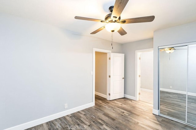 unfurnished bedroom with ceiling fan, wood-type flooring, and a closet