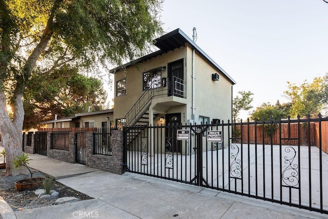 view of front facade with a gate, stucco siding, a fenced front yard, and stairway