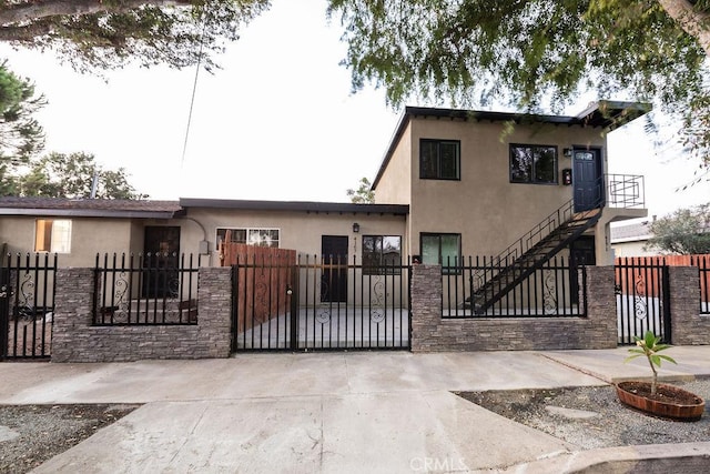 view of front facade with stucco siding, a fenced front yard, and a gate