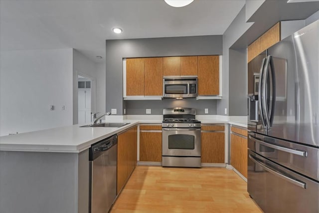 kitchen featuring appliances with stainless steel finishes, sink, light hardwood / wood-style flooring, and kitchen peninsula