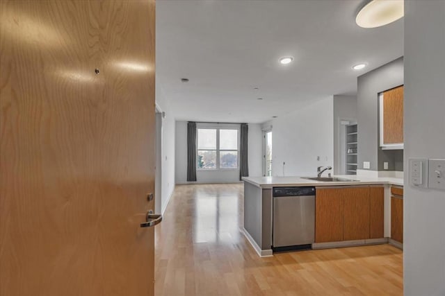 kitchen featuring dishwasher, sink, kitchen peninsula, and light wood-type flooring