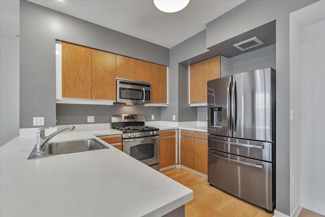 kitchen featuring stainless steel appliances, sink, and light hardwood / wood-style flooring