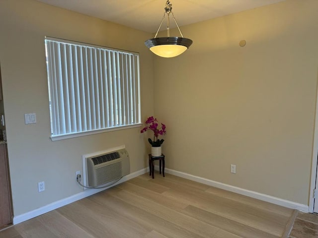 unfurnished room featuring light wood-type flooring and a wall mounted air conditioner