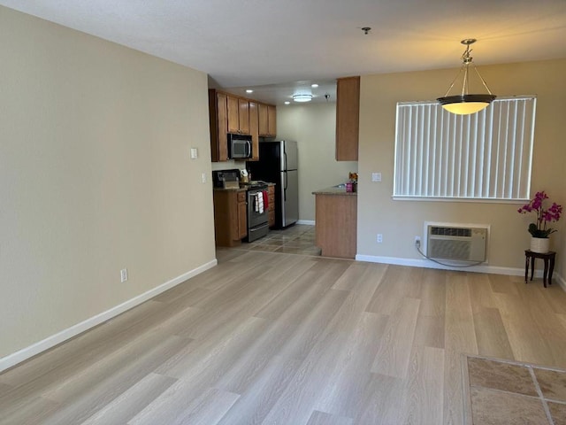 kitchen featuring a wall mounted AC, hanging light fixtures, light wood-type flooring, black range with electric cooktop, and stainless steel fridge