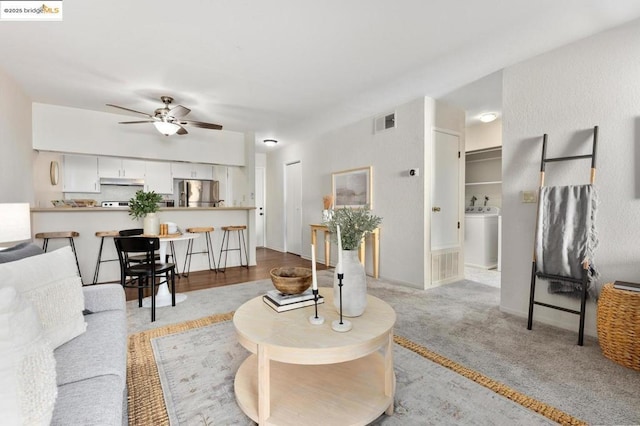 carpeted living room featuring ceiling fan and washer / clothes dryer