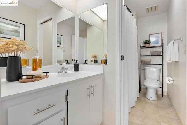 bathroom with toilet, vanity, and tile patterned flooring