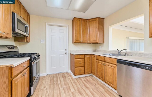 kitchen with appliances with stainless steel finishes, light hardwood / wood-style floors, and sink