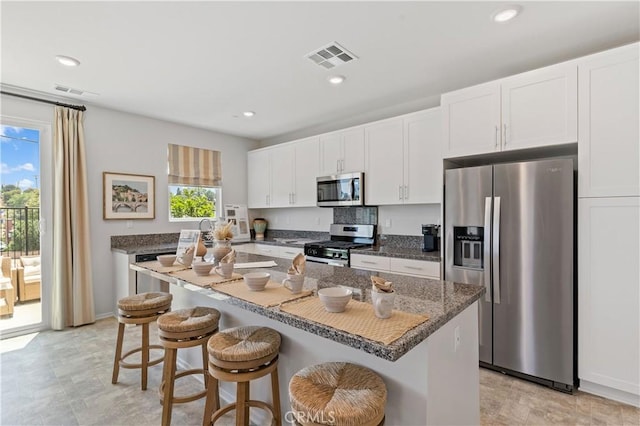 kitchen featuring a kitchen bar, appliances with stainless steel finishes, white cabinetry, and a kitchen island