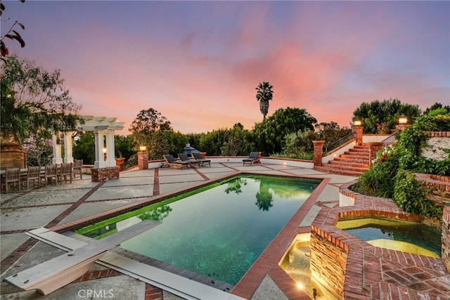 pool at dusk with a diving board, a pergola, an in ground hot tub, and a patio