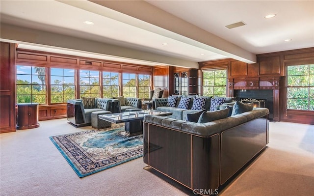 carpeted living room featuring beam ceiling and wooden walls