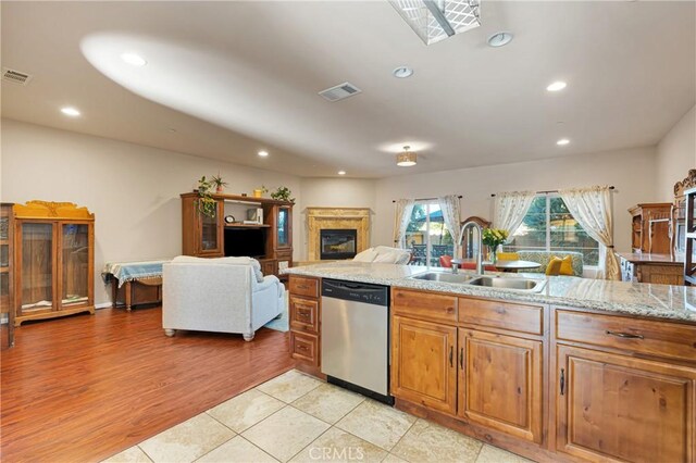 kitchen with light stone countertops, light tile patterned flooring, dishwasher, and sink