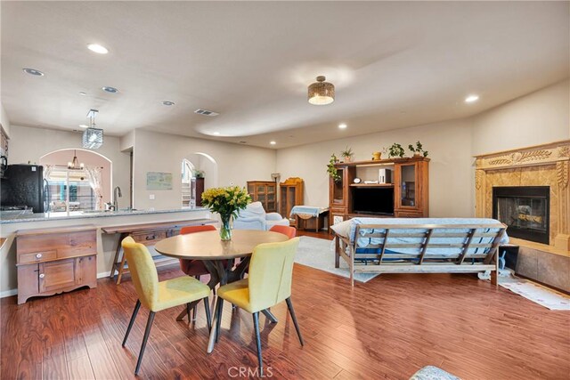 dining room with a fireplace, dark wood-type flooring, sink, and a chandelier