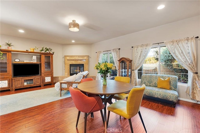 dining room with hardwood / wood-style floors, a premium fireplace, and a healthy amount of sunlight