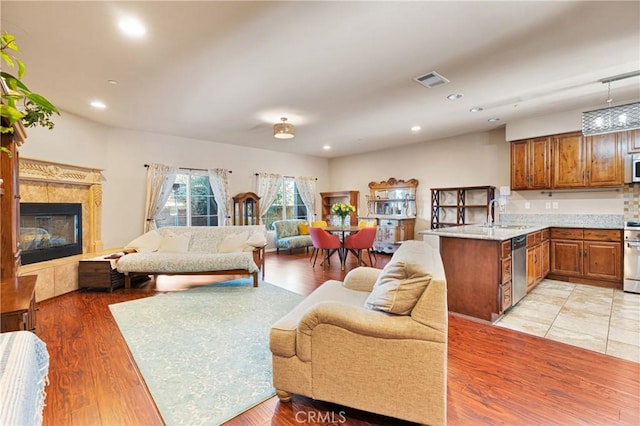 living room with a tiled fireplace, sink, and light hardwood / wood-style floors