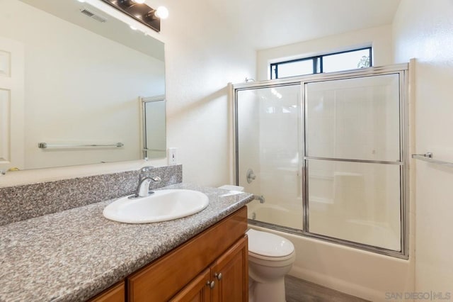 full bathroom with toilet, enclosed tub / shower combo, and vanity