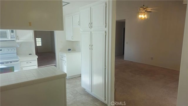 kitchen with white cabinetry, light colored carpet, white appliances, and tile counters