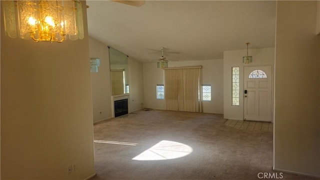 foyer entrance featuring ceiling fan with notable chandelier, light colored carpet, and lofted ceiling