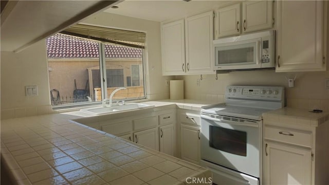 kitchen with tile counters, sink, white appliances, and white cabinetry