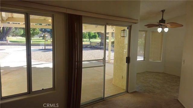 doorway with ceiling fan and carpet flooring