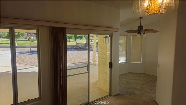 doorway with carpet flooring, ceiling fan with notable chandelier, and plenty of natural light