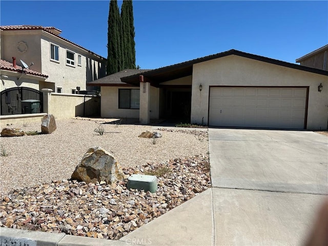 view of front facade with an attached garage, fence, concrete driveway, and stucco siding