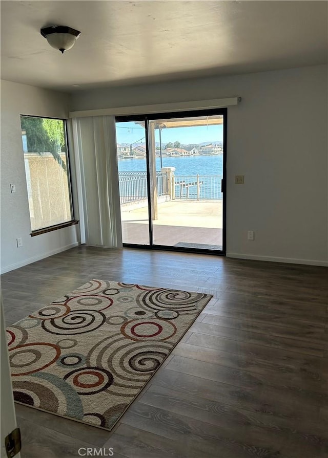 empty room with a water view and dark wood-type flooring