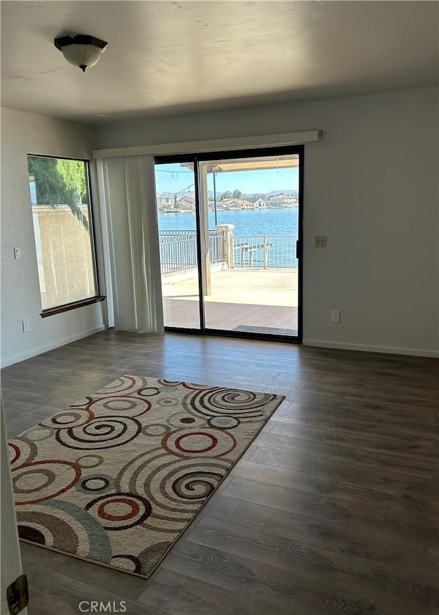 spare room featuring a water view, baseboards, and wood finished floors