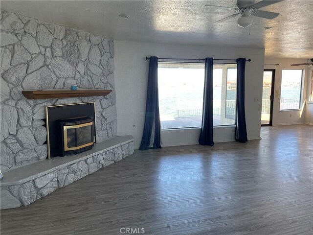 unfurnished living room with ceiling fan, a fireplace, hardwood / wood-style floors, and a textured ceiling