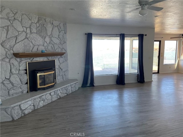 unfurnished living room featuring a textured ceiling, ceiling fan, a fireplace, and wood finished floors