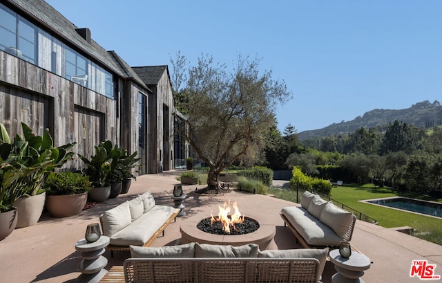 view of patio / terrace featuring a mountain view and an outdoor living space with a fire pit