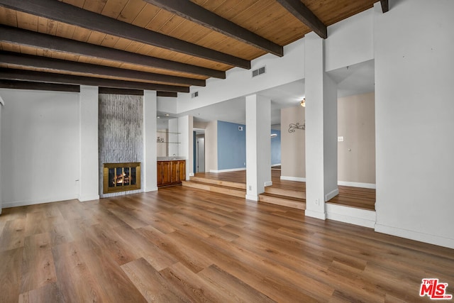 unfurnished living room with wood-type flooring, a large fireplace, beamed ceiling, and wooden ceiling