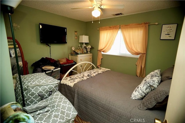 bedroom with a ceiling fan, visible vents, and a textured ceiling