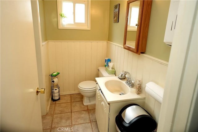 half bath featuring wainscoting, vanity, toilet, and tile patterned floors