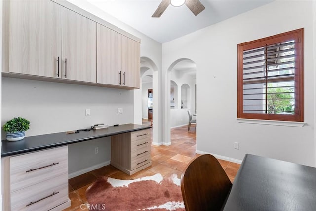 office featuring ceiling fan, light tile patterned floors, and built in desk