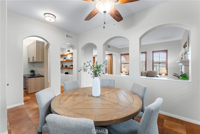 dining space featuring ceiling fan, light tile patterned floors, and built in features